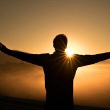 silhouette photo of man on cliff during sunset